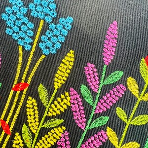 K&ouml;nnte beinhalten: Gestickte Blumenmuster auf schwarzem Stoffhintergrund. Das Design zeigt blaue, gelbe, gr&uuml;ne und rosa Blumen.