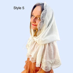 K&ouml;nnte beinhalten: Ein wei&szlig;er Spitzenschleier mit floralen Stickereien und gewellten Kanten. Der Schleier ist &uuml;ber Kopf und Schultern drapiert. Der Text "Style 5" befindet sich in der oberen linken Ecke.