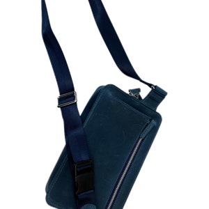 May include: A dark blue leather crossbody bag with a zipped pocket and an adjustable strap.
