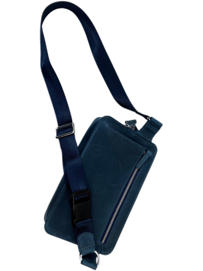 May include: A dark blue leather crossbody bag with a zipped pocket and an adjustable strap.