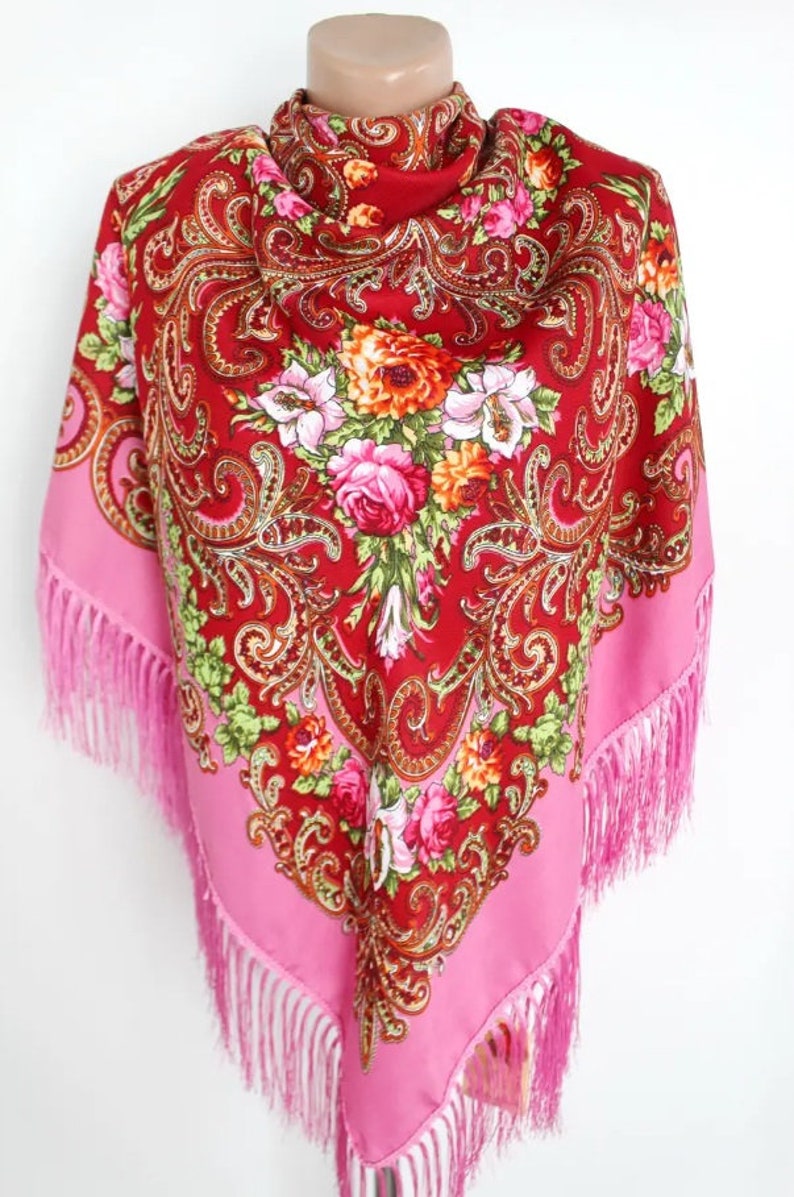 Pu&ograve; includere: Un foulard di seta rosso e rosa con motivi floreali e accenti dorati. Il foulard ha frange rosa sui bordi.
