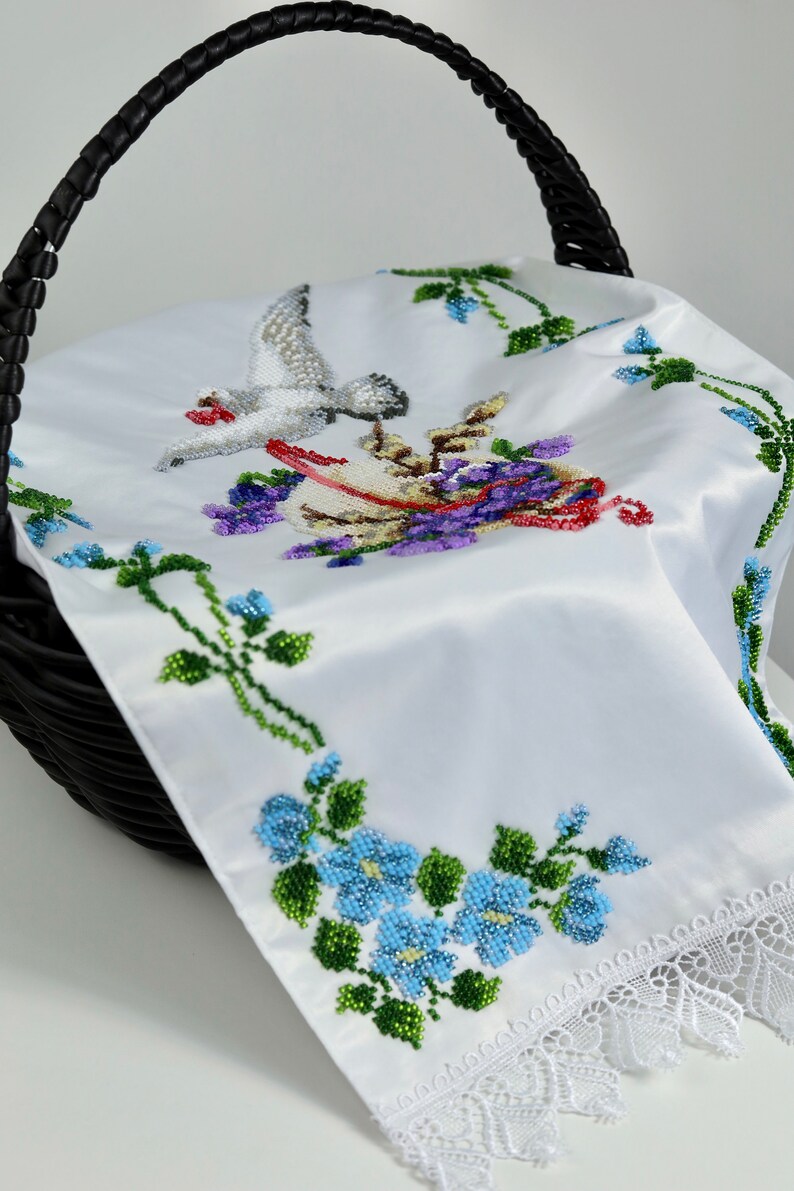 May include: White satin Easter basket liner featuring a beaded design of a dove and flowers. The liner has a lace trim and is ideal for adding a touch of elegance to your Easter basket.