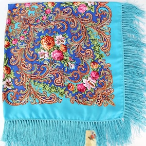 Pu&ograve; includere: Un foulard di seta blu turchese con un motivo floreale e paisley. Il foulard ha un bordo a frangia.