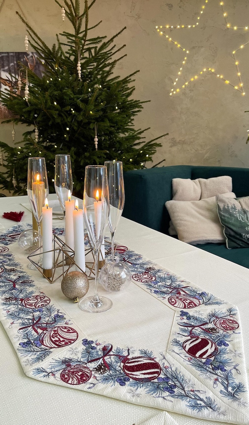Puede incluir: Una mesa navide&ntilde;a festiva con un &aacute;rbol decorado al fondo. La mesa est&aacute; decorada con copas de champ&aacute;n, velas encendidas y un camino de mesa decorativo con adornos navide&ntilde;os. Un portavelas geom&eacute;trico dorado y un adorno brillante realzan el ambiente festivo.