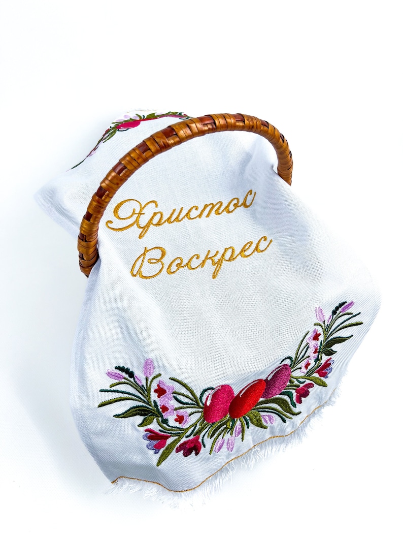 Pu&ograve; includere: Un cesto di Pasqua in tessuto bianco con un manico intrecciato. Il cesto &egrave; decorato con fiori ricamati e il testo "Христос Воскрес" in filo d'oro.
