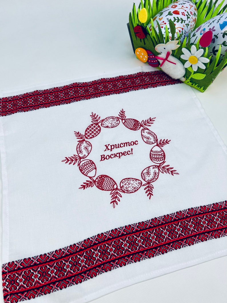 May include: White kitchen towel with red embroidered border and a wreath of red Easter eggs with the text "Христос Воскрес!" in the center.