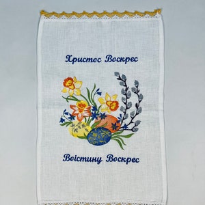 Puede incluir: Toalla de t&eacute; de lino blanco con narcisos amarillos, campanillas azules y ramas de sauce bordadas. El texto "Христос Воскрес" y "Воистину Воскрес" est&aacute; bordado en hilo azul.