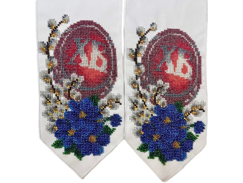 May include: Two white fabric panels with embroidered designs. Each panel features a red egg shape with the letters "XB" in white, surrounded by white and gold floral accents and blue beaded flowers.