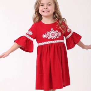K&ouml;nnte beinhalten: Ein rotes Leinenkleid mit wei&szlig;en gestickten Blumen und Spitzenbesatz. Das Kleid hat einen runden Ausschnitt und 3/4 &Auml;rmel.