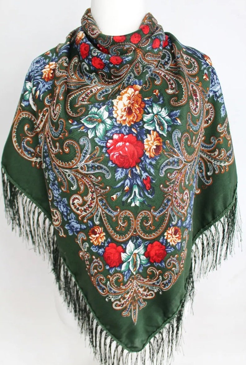 May include: A green silk scarf with a floral pattern and fringe. The pattern features red, orange, yellow, blue, and green flowers on a dark green background.