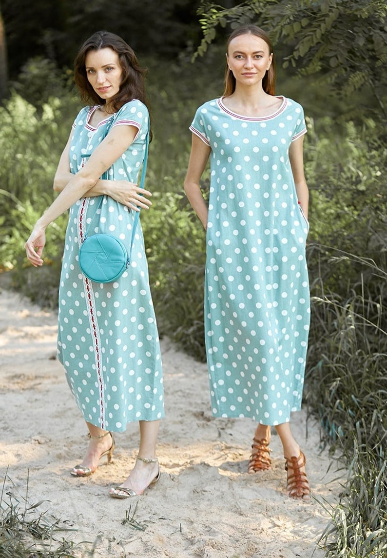 Puede incluir: Dos mujeres vistiendo vestidos de lunares azul claro con lunares blancos. Los vestidos tienen mangas cortas y un escote redondo. Una mujer lleva un peque&ntilde;o bolso redondo de color turquesa. Ambas mujeres llevan sandalias.