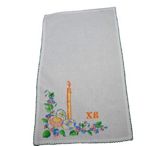 Puede incluir: Toalla de cocina blanca bordada con un borde verde. El bordado presenta una vela, huevos de Pascua, flores y el texto cir&iacute;lico "XB".