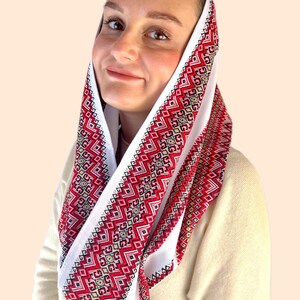 May include: White head scarf with red and gold embroidered geometric patterns. The scarf is folded and worn around the head. Style 3.