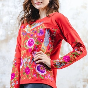 Puede incluir: Camiseta roja de manga larga con bordado floral y de p&aacute;jaros de colores.