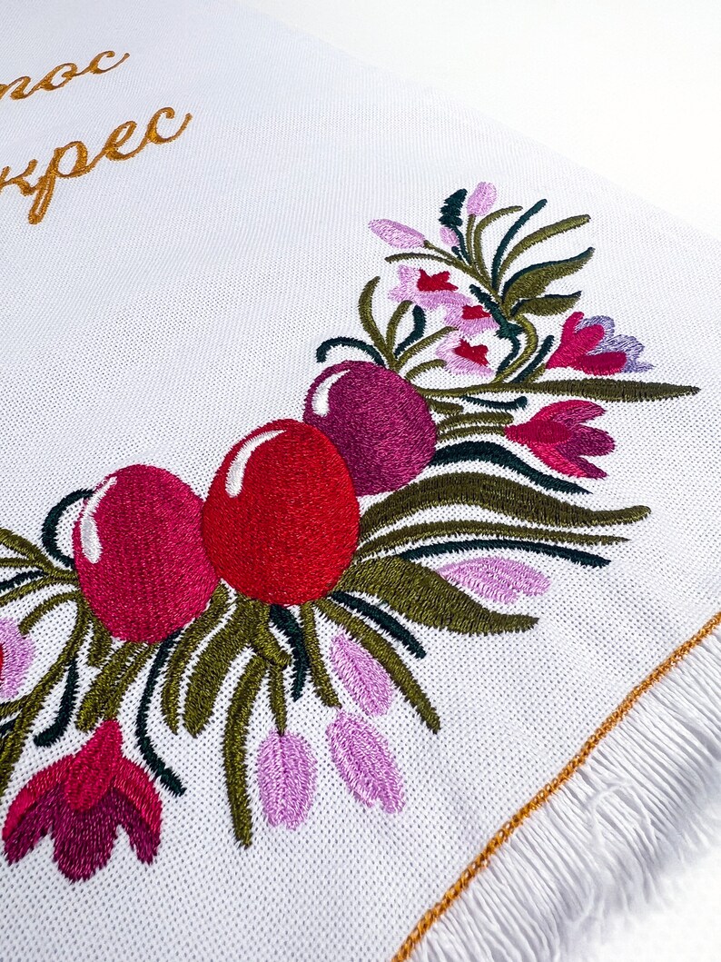 Pu&ograve; includere: Tovagliolo da cucina bianco ricamato con un motivo floreale con fiori rosa, rossi e verdi. Il testo "noc ypec" &egrave; ricamato in filo dorato nella parte superiore del tovagliolo.