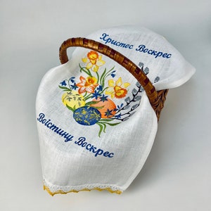 Puede incluir: Forro de cesta de Pascua de lino blanco con narcisos amarillos bordados, huevos azules y amarillos, y el texto "Христос Воскрес" y "Воистину Воскрес".