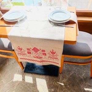 Linen table runner with red embroidered floral pattern