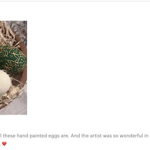 May include: A collection of six hand-painted decorative eggs in a wooden bowl filled with straw. The eggs feature various designs, including floral patterns and gold accents, in shades of green, white, and gold. The eggs are a unique Easter or home decor item.
