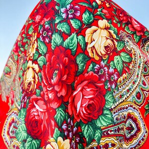 Peut inclure: Tissu rouge avec un motif floral compos&eacute; de roses rouges, jaunes et vertes. Le tissu pr&eacute;sente un motif paisley dans le coin inf&eacute;rieur droit.
