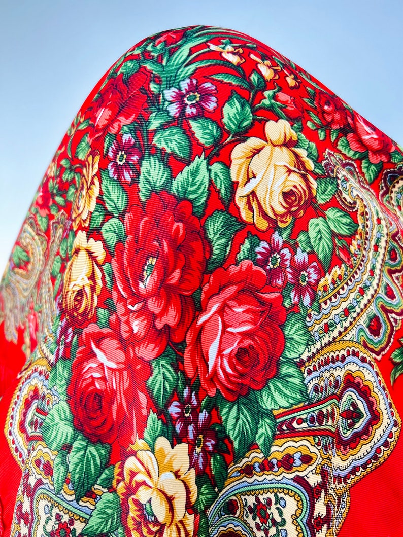 Peut inclure: Tissu rouge avec un motif floral compos&eacute; de roses rouges, jaunes et vertes. Le tissu pr&eacute;sente un motif paisley dans le coin inf&eacute;rieur droit.