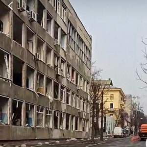 K&ouml;nnte beinhalten: Au&szlig;enansicht eines mehrst&ouml;ckigen Betongeb&auml;udes mit zahlreichen zerbrochenen Fenstern. Klimaanlagen sind an der Fassade zu sehen. Eine Stra&szlig;e mit geparkten Fahrzeugen und ein gelbes Geb&auml;ude im Hintergrund.