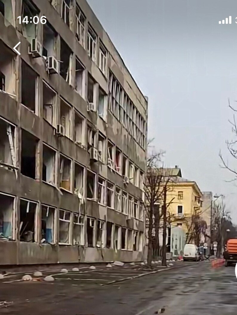 K&ouml;nnte beinhalten: Au&szlig;enansicht eines mehrst&ouml;ckigen Betongeb&auml;udes mit zahlreichen zerbrochenen Fenstern. Klimaanlagen sind an der Fassade zu sehen. Eine Stra&szlig;e mit geparkten Fahrzeugen und ein gelbes Geb&auml;ude im Hintergrund.