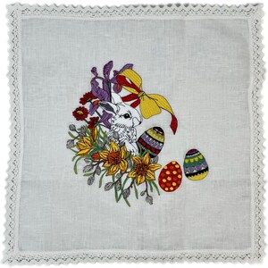 May include: White linen tea towel with embroidered Easter bunny, flowers, and eggs. The bunny is surrounded by yellow daffodils, purple irises, and red flowers. The eggs are decorated with colorful patterns.
