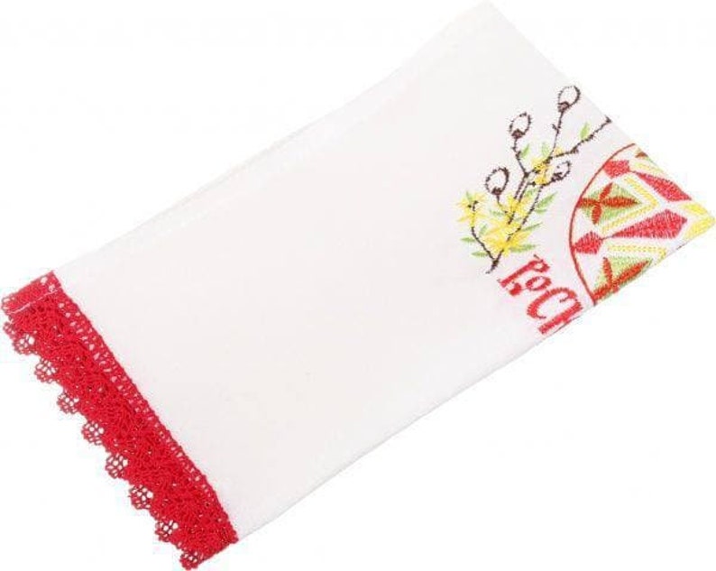 Peut inclure: Serviette de cuisine blanche avec une bordure en dentelle rouge brod&eacute;e et un motif d'&oelig;uf de P&acirc;ques brod&eacute; color&eacute;. Le motif comprend une fleur jaune et le mot "Joyeux" en rouge.