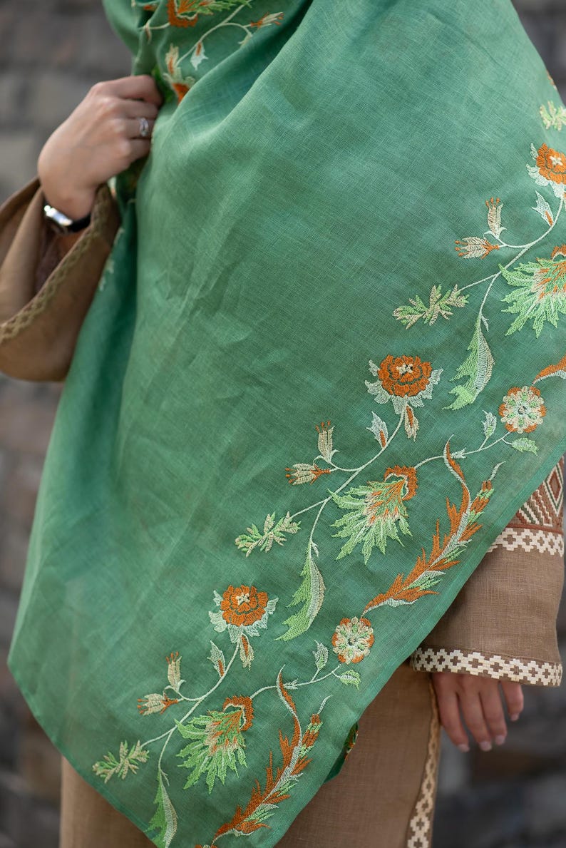 May include: A green shawl with embroidered floral designs in shades of orange, white, and green.