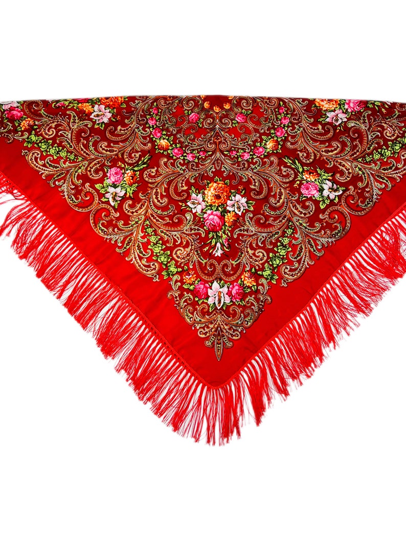 May include: A red shawl with a floral pattern and gold accents. The shawl has a fringe border.