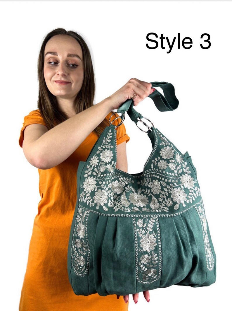 Peut inclure: Sac fourre-tout vert d'eau avec broderie florale blanche. Le sac a un design pliss&eacute; et une large bandouli&egrave;re avec des anneaux en m&eacute;tal argent&eacute;. Le texte "Style 3" est visible.