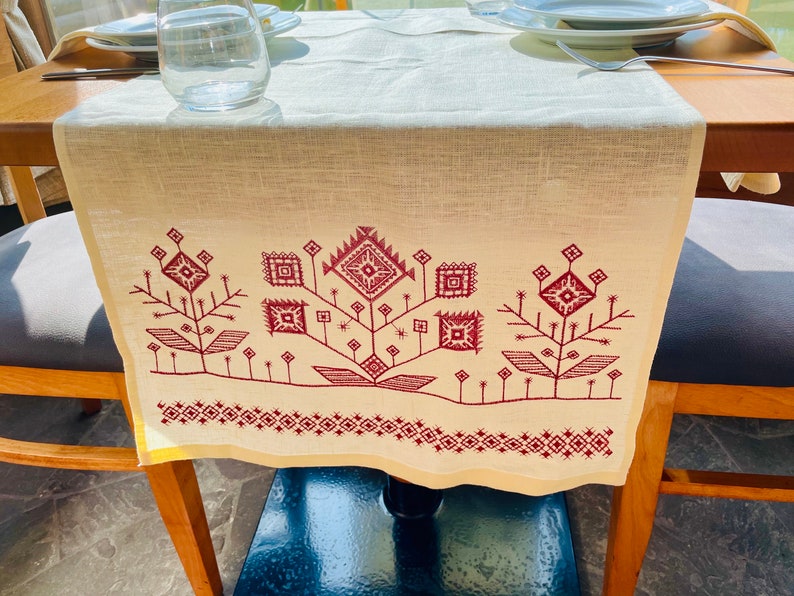 Linen table runner with red embroidered floral pattern