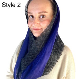 May include: A blue fabric head covering with black lace trim. The lace trim is on the edge of the fabric and is a decorative element.