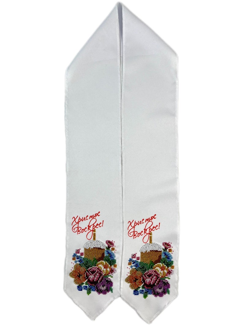 May include: White liturgical stole with embroidered floral and cake design. The stole features the text "Christ is Risen!" in red script. The embroidery includes a cake, flowers, and colorful beads.