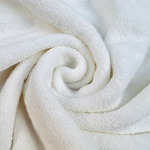 May include: A close-up of a white, fluffy towel with a soft, textured surface. The towel is folded and twisted, creating a spiral pattern.
