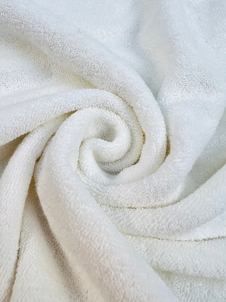 May include: A close-up of a white, fluffy towel with a soft, textured surface. The towel is folded and twisted, creating a spiral pattern.