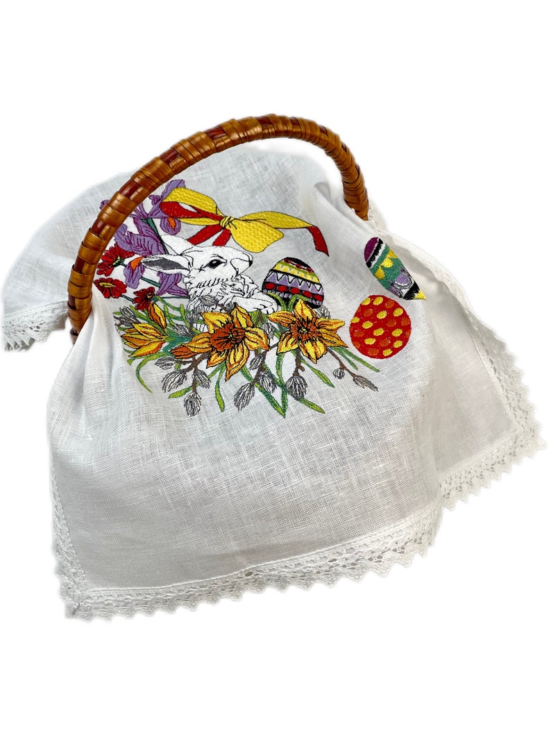 May include: White linen Easter basket liner with embroidered bunny, flowers, and colorful eggs. The liner has a white lace trim.