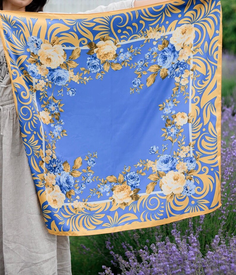 May include: A blue and gold floral patterned scarf with a yellow and blue floral design. The scarf is made of a soft, silky material and has a delicate, feminine feel.