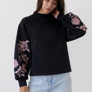 Black sweatshirt with pink floral embroidered sleeves