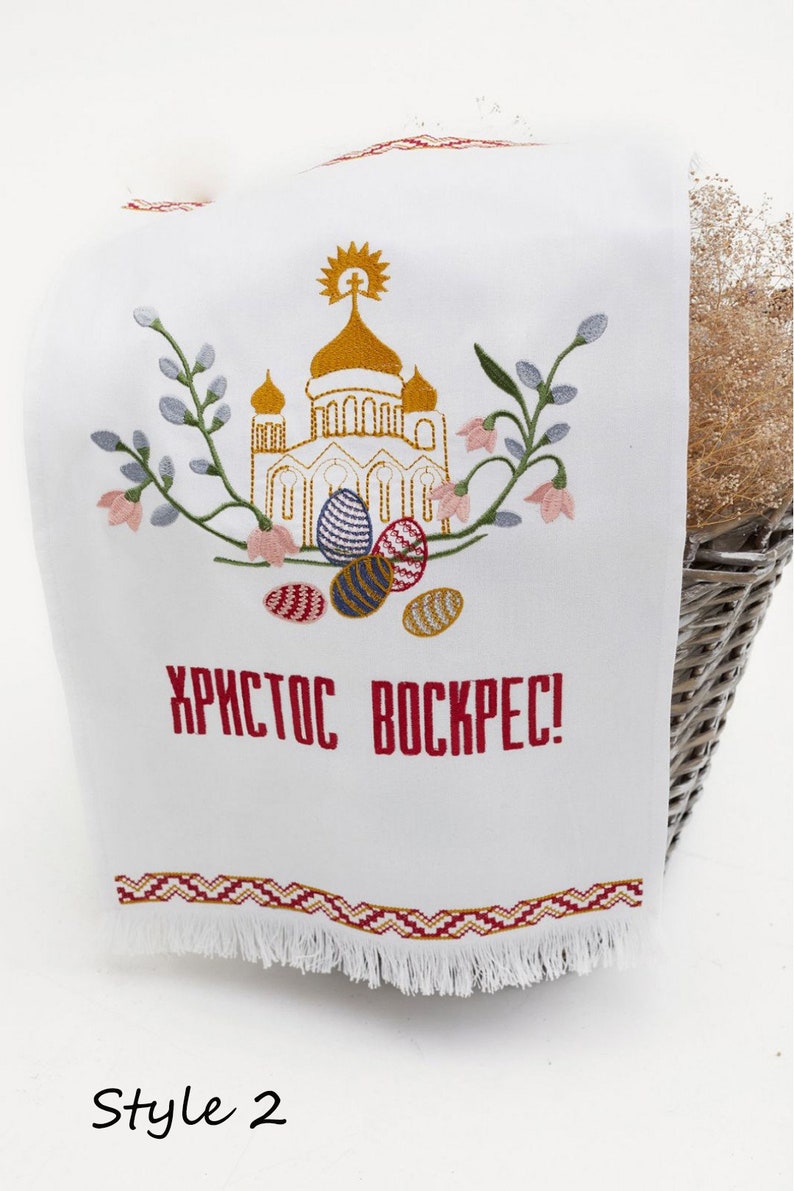 Op de afbeelding: Witte geborduurde keukendoek met een gouden kerk, bloemen en kleurrijke paaseieren. De tekst "ХРИСТОС ВОСКРЕС!" is geborduurd in rood.