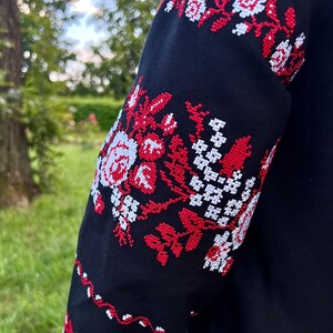 K&ouml;nnte beinhalten: Schwarzer bestickter &Auml;rmel mit rotem und wei&szlig;em Blumenmuster.