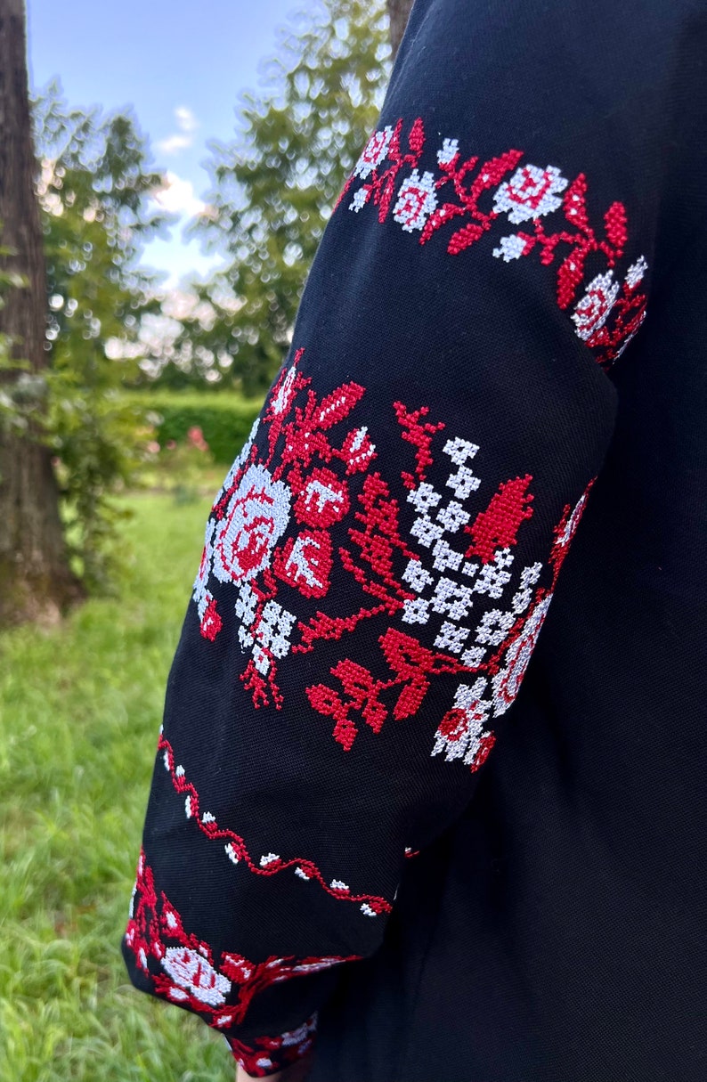 K&ouml;nnte beinhalten: Schwarzer bestickter &Auml;rmel mit rotem und wei&szlig;em Blumenmuster.