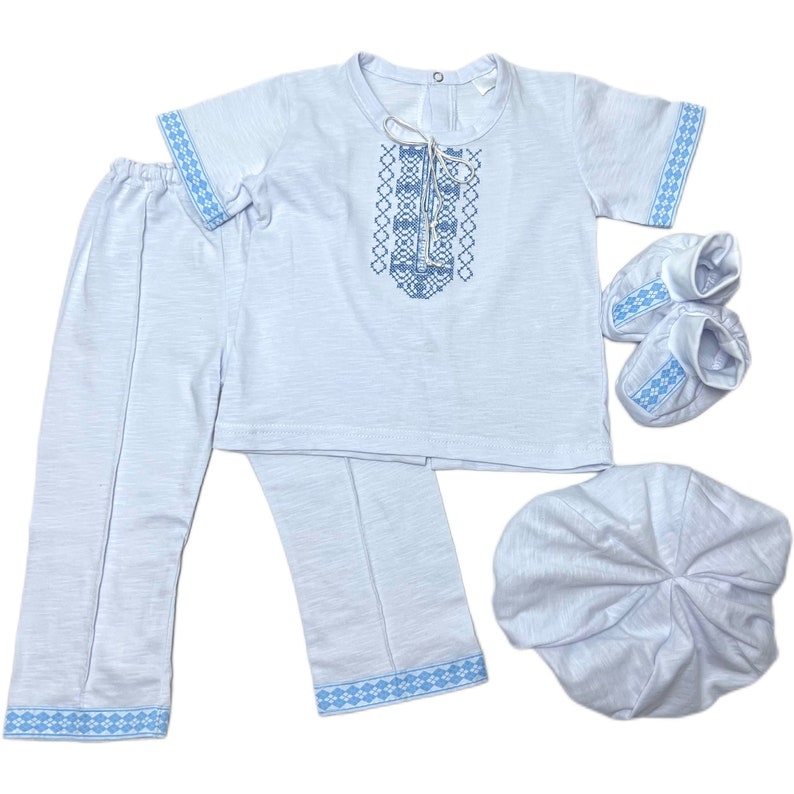 May include: A light blue baby outfit set with embroidered details. The set includes a short-sleeved shirt, pants, a hat, and booties.