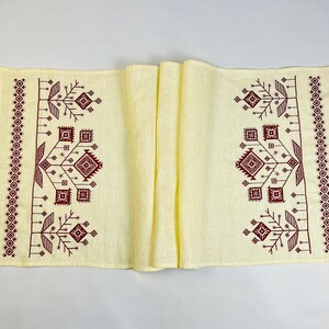 Linen table runner with red embroidered floral pattern