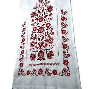 K&ouml;nnte beinhalten: Wei&szlig;er Leinenstoff mit roter und schwarzer Stickerei in Blumenform. Das Design zeigt ein zentrales Blumenmotiv mit kleineren Blumenmotiven an den R&auml;ndern.
