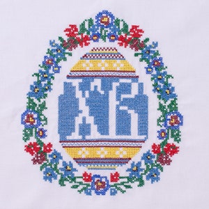 Peut inclure: Un tissu blanc avec un motif brod&eacute; bleu, jaune, rouge et vert d'un &oelig;uf entour&eacute; de fleurs.