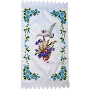 May include: White satin fabric with a white dove and a purple and yellow egg embroidered on it. The fabric is trimmed with white lace.