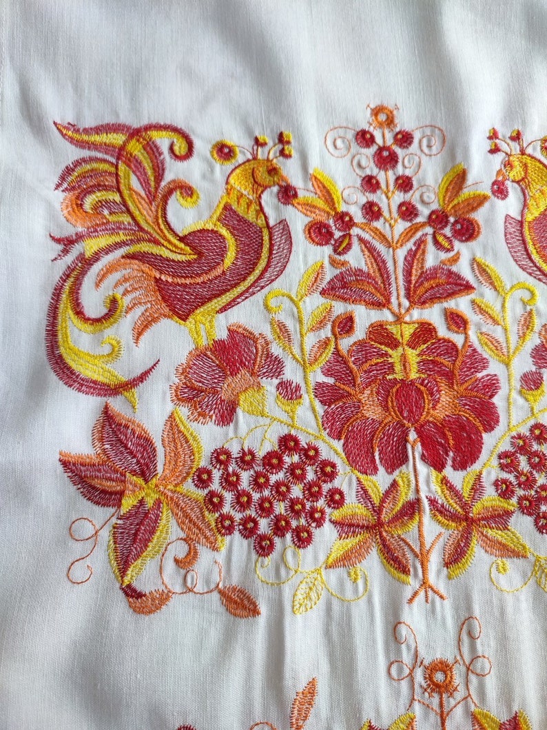 May include: Embroidered design featuring two stylized birds with yellow, orange, and red details. The birds are surrounded by floral motifs with red, orange, and yellow flowers and leaves.