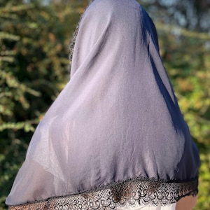 May include: A black sheer scarf with a black lace trim. The scarf is draped over a person's head and shoulders.