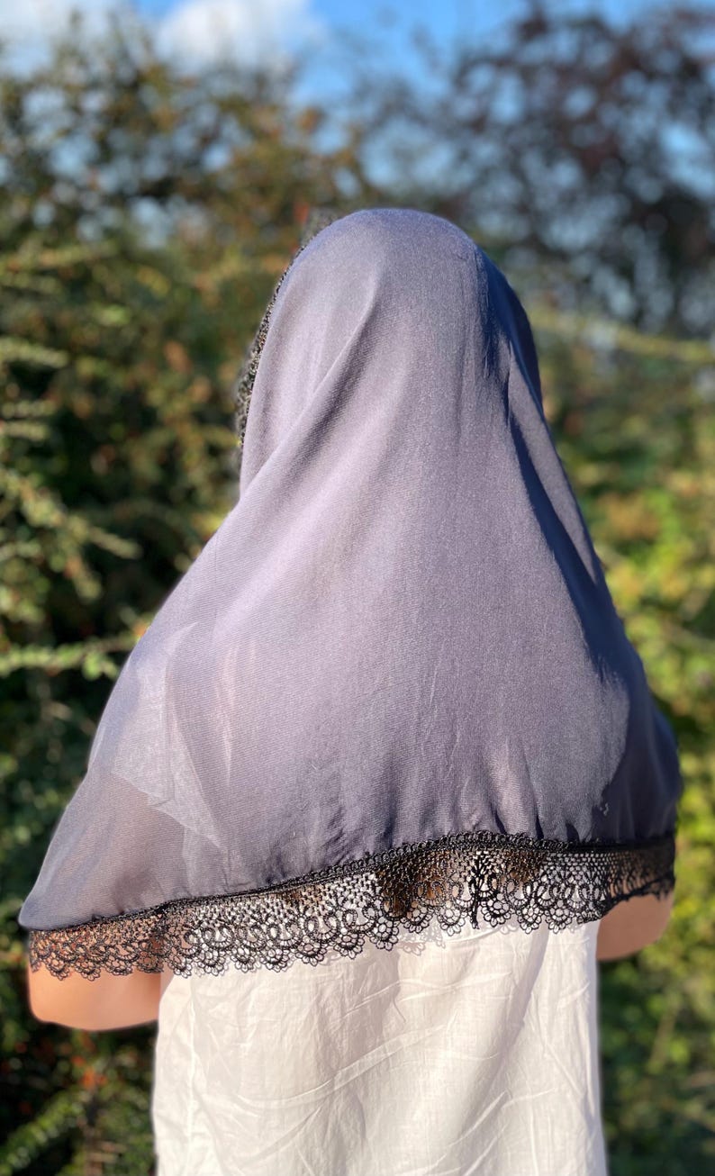 May include: A black sheer scarf with a black lace trim. The scarf is draped over a person's head and shoulders.